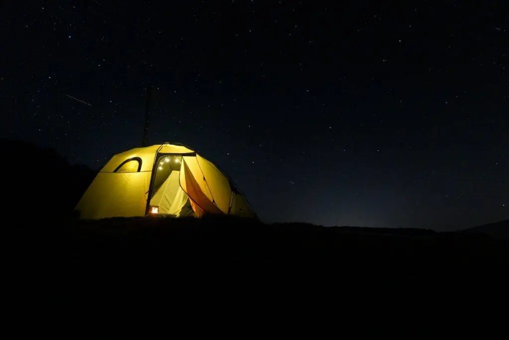 A glowing tent under a starry night sky