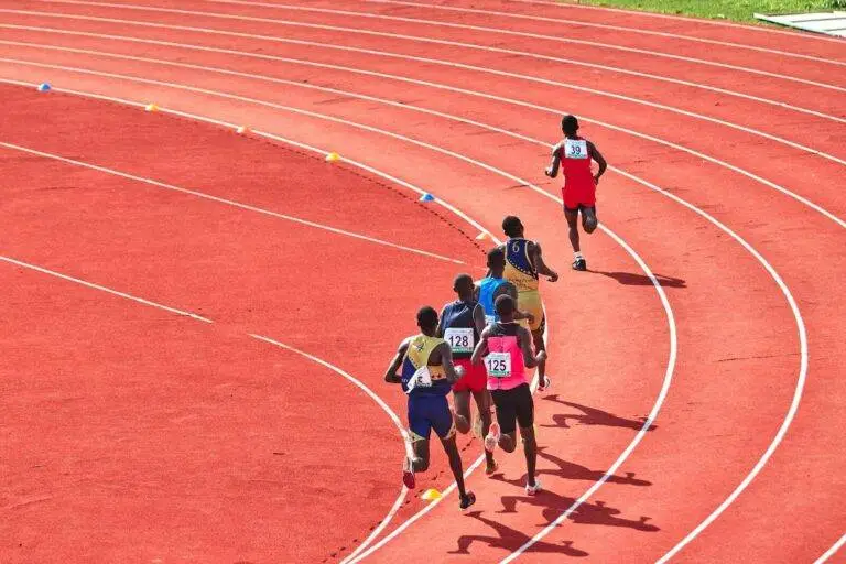 A group of athletes running on a curved outdoor track in a competitive race.