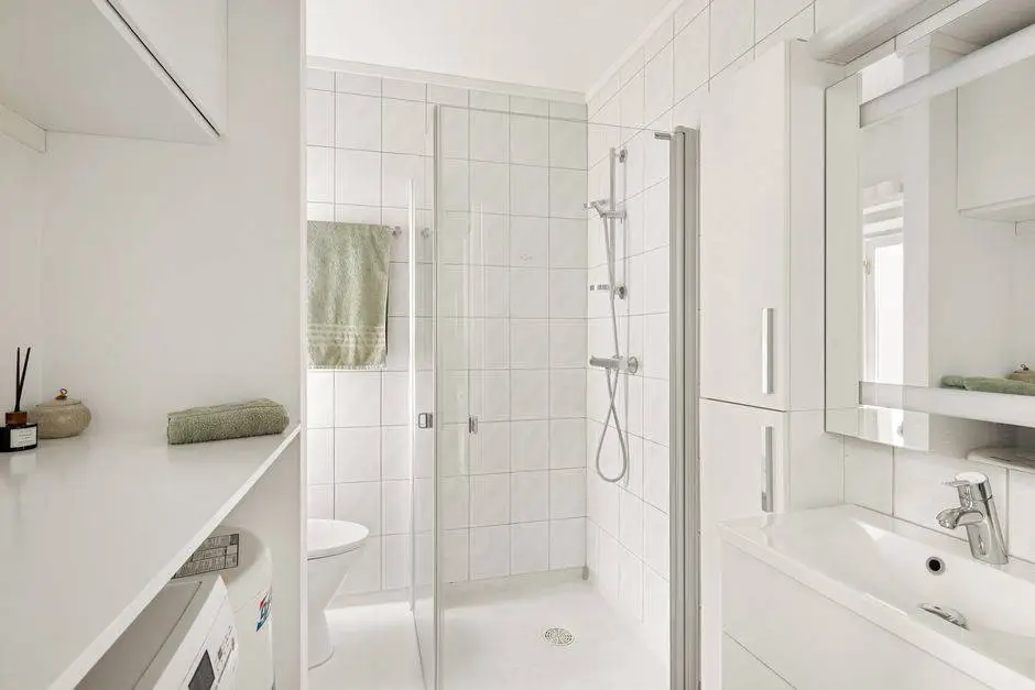 Bright, minimalist white bathroom featuring a sleek design with glass shower and modern fixtures.