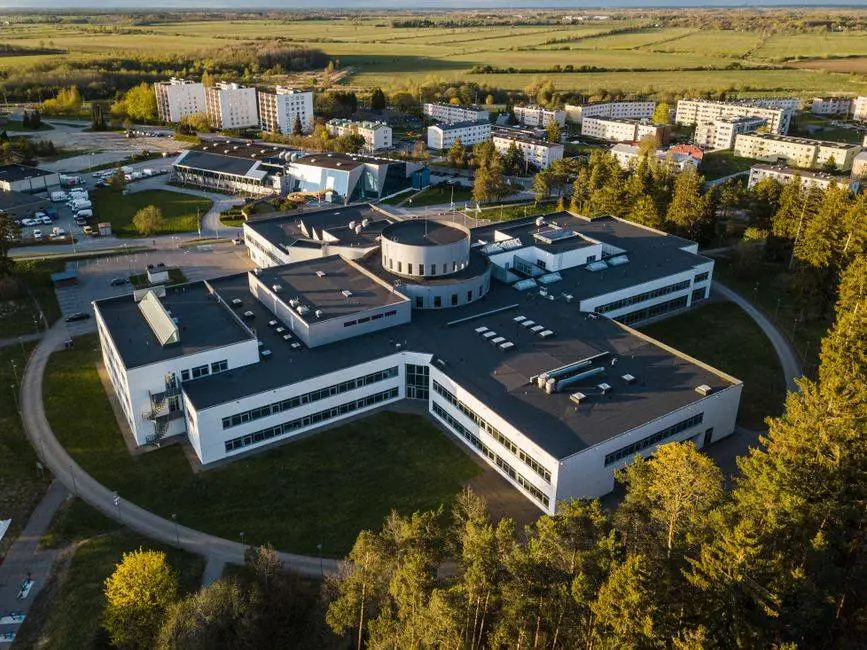 Drone shot of an academic building complex surrounded by trees and apartments at sunset.