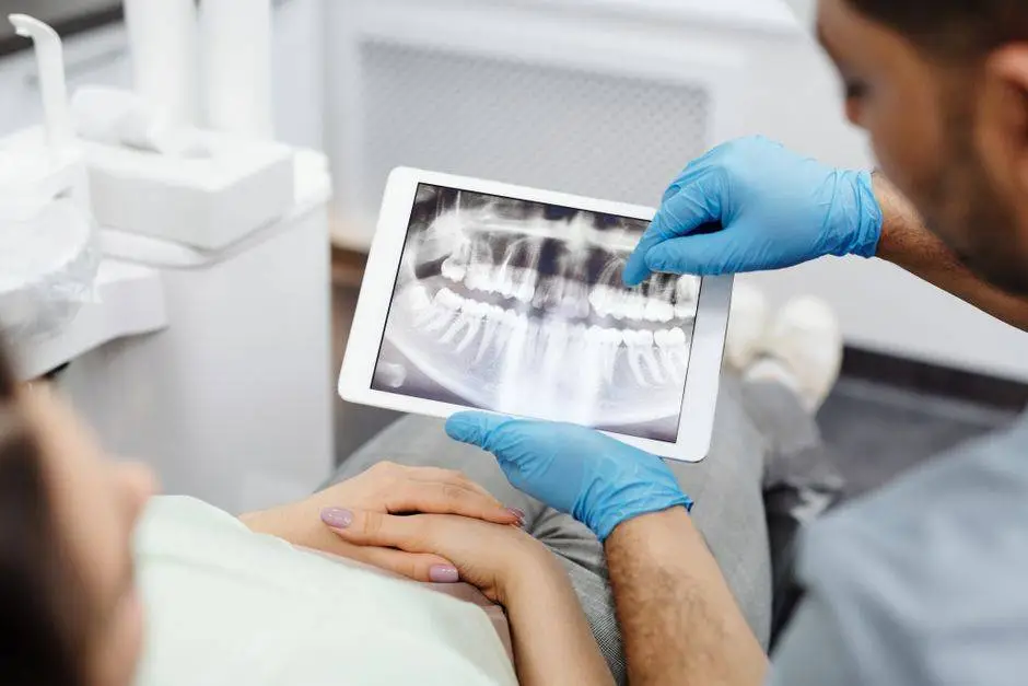 Dentist reviewing a dental X-ray with a patient using a tablet, highlighting modern dental care.