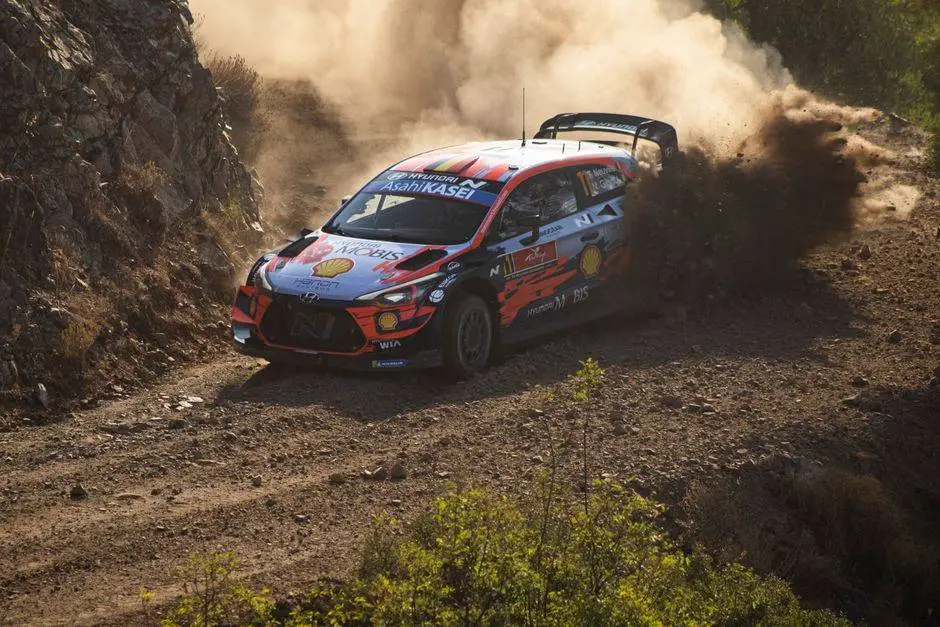 High-speed rally car navigating a dusty dirt road, showcasing endurance and precision driving.